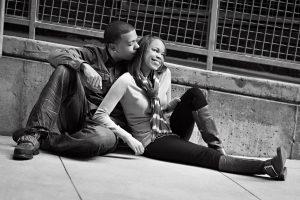 African American couple sitting, smiling and leaning on concrete