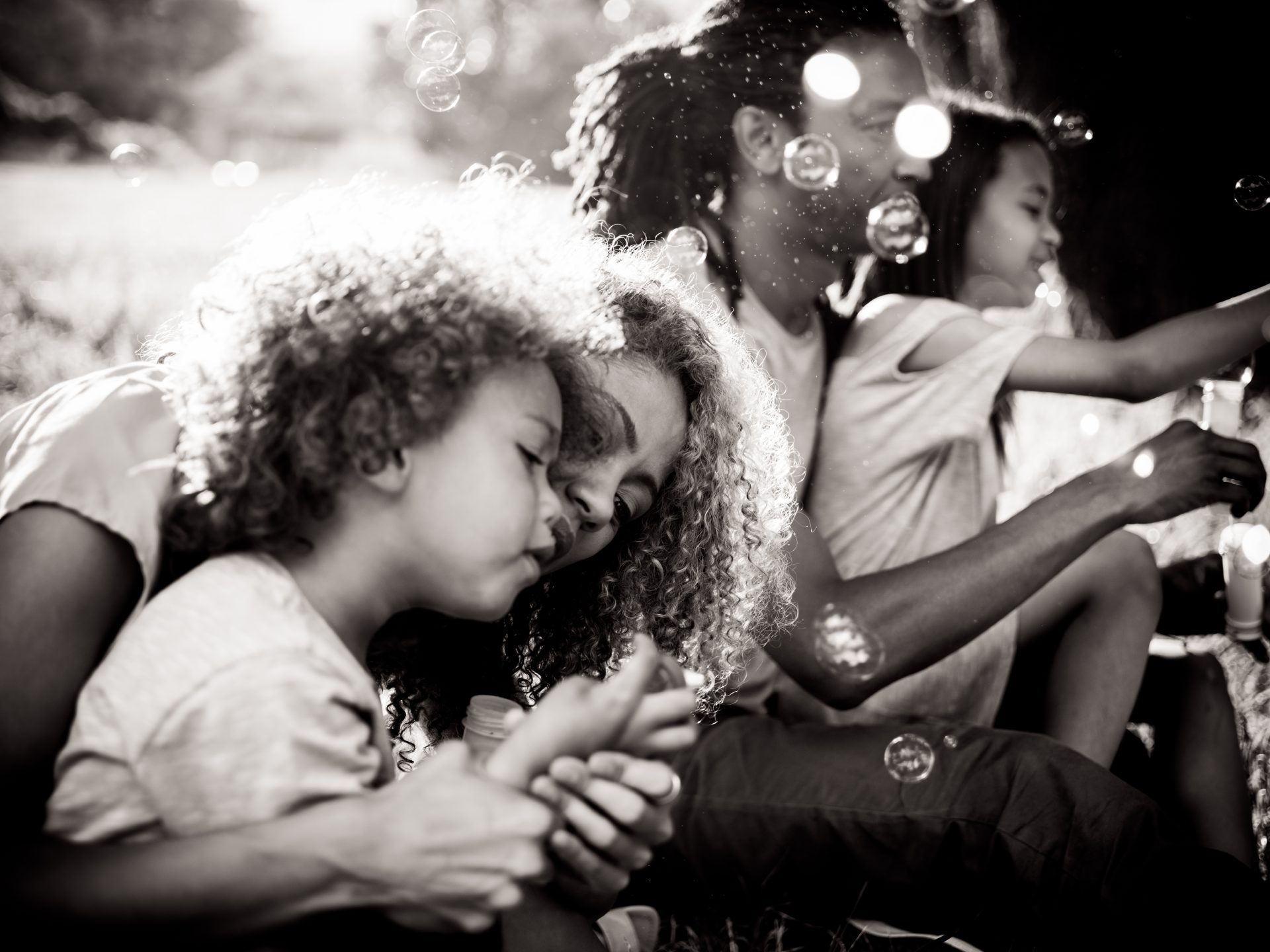 Black and white image of family blowing bubbles